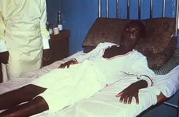 Male with Lassa fever in 1977  lying in a hospital bed in Segbwema, Sierra Leone. Note his dazed, somnolent facial expression due to his weakness, and exhaustion.