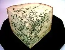 A corner of cheese with greenish streaks through it