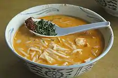 Katong laksa, con salsa piccante e pezzi di foglia di laksa in un cucchiaio